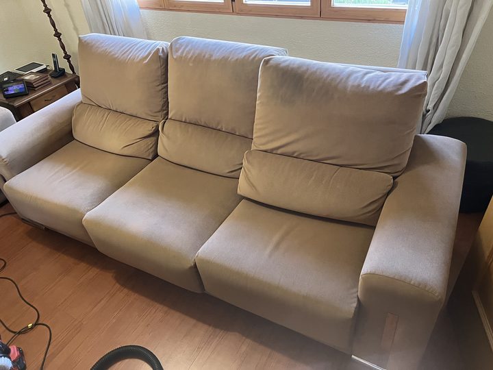 Sofá de tres plazas de microfibra beige con el asiento oscurecido por el uso, antes de la limpieza, en un domicilio de Getafe