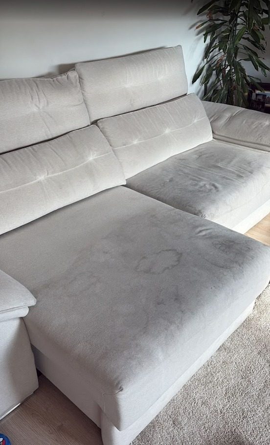 Sofá chaiselongue beige con manchas oscuras en el asiento, antes de la limpieza