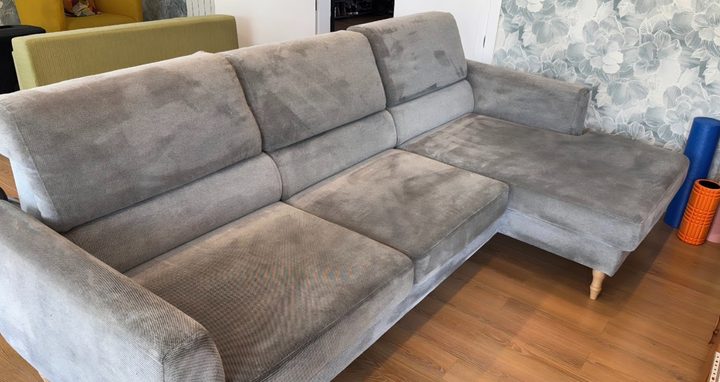 Sofá gris con chaiselongue y manchas extendidas por todo el asiento, antes de limpiar